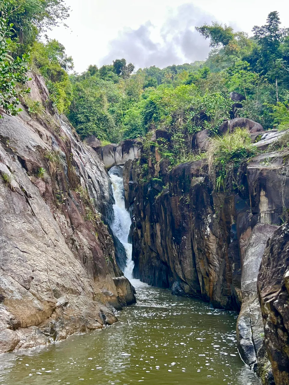 Waterfall dropping into the rock gorge pool at Charco El Hippie